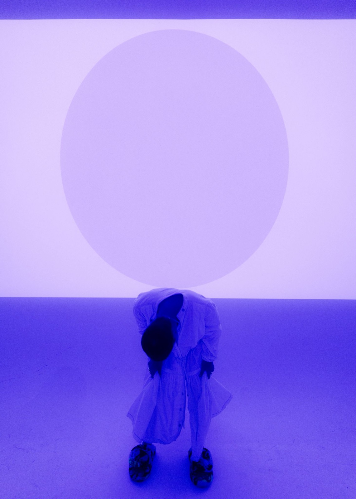 Hooded figure beneath a luminous purple circle